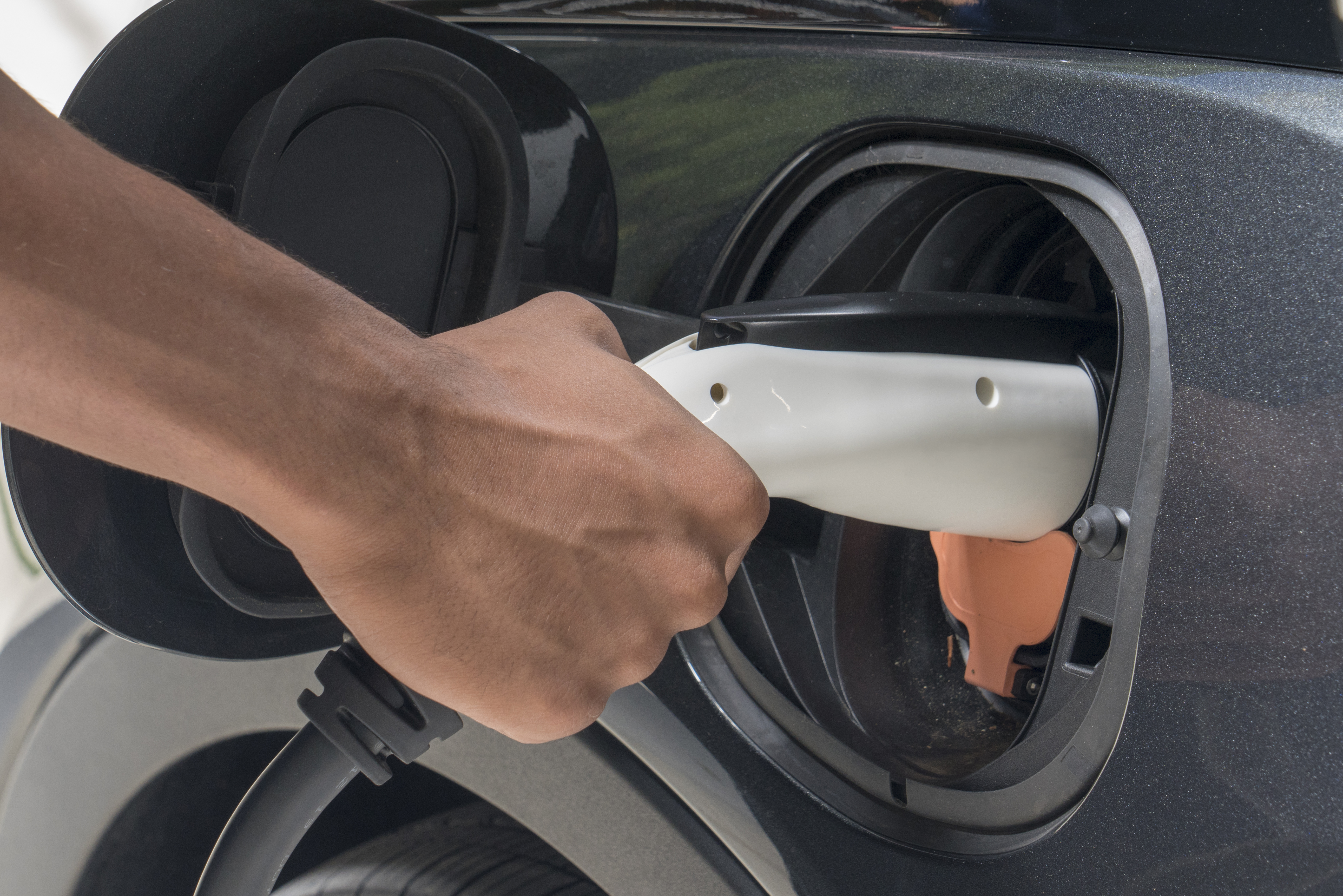 Hand plugging a charger into an electric car
